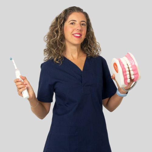 Dentista en Sevilla Este, Dra. Elisa Fernández Santa Cruz daza, , con el modelo de una boca y un cepillo de dientes eléctrico.